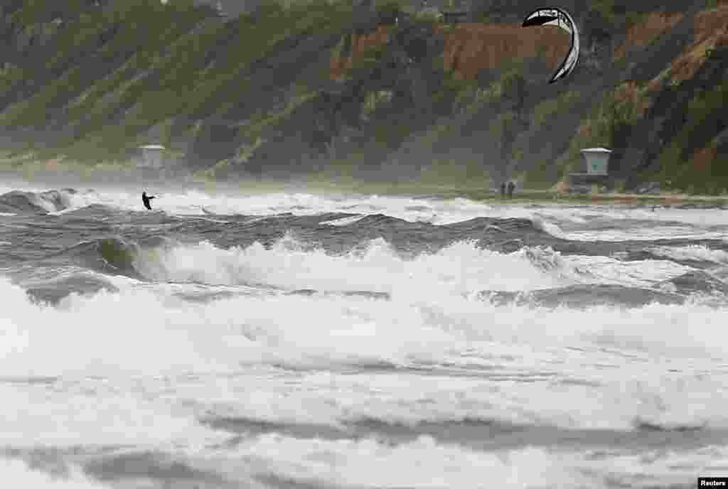 Seorang penerbang layang mengarungi laut yang bergolak saat badai musim gugur menghantam tepian pantai Cardiff, California, 9 Oktober 2013.