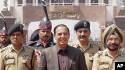 Pakistan's Interior Secretary Qamar-uz-Zaman Chaudhry walks with Indian Border Security Force officers as he arrives on the Indian side of the border at Wagah, India, March 27, 2011