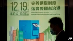 Seorang pria berjalan melewati poster mempromosikan pemilihan legislatif di Hong Kong, Selasa, 23 November 2021. Hong KOng akan melangsungkan pemilu tanggal 19 Desember 2021. (AP/Kin Cheung)