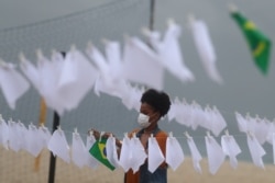 A member of the Rio de Paz NGO places white handkerchiefs that symbolize a farewell, to pay tribute to Brazil's 600,000 COVID-19 deaths, at Copacabana beach in Rio de Janeiro, Brazil, October 8, 2021.