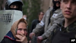 An elderly woman watch as a group of pro-Russian demonstrators storm the military Prosecutor's Office in Donetsk, Ukraine, May 4, 2014. 