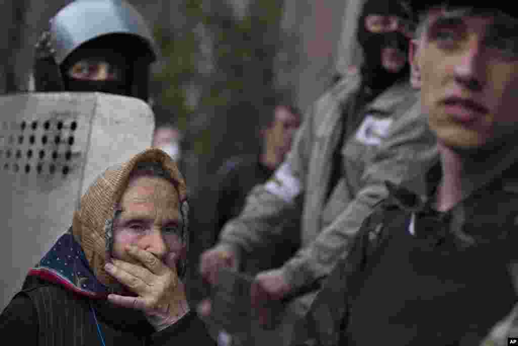 An elderly woman watch as a group of pro-Russian demonstrators storm the military Prosecutor's Office in Donetsk, Ukraine, May 4, 2014.