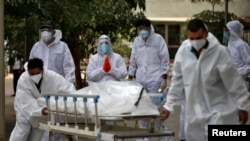 Rođaci reagiraju dok zdravstveni radnici u mrtvačnici u Ahmedabadu u Indiji, 8. svibnja 2021., izvlače nosila koja nose tijelo osobe koja je umrla od koronavirusne bolesti (COVID-19). 