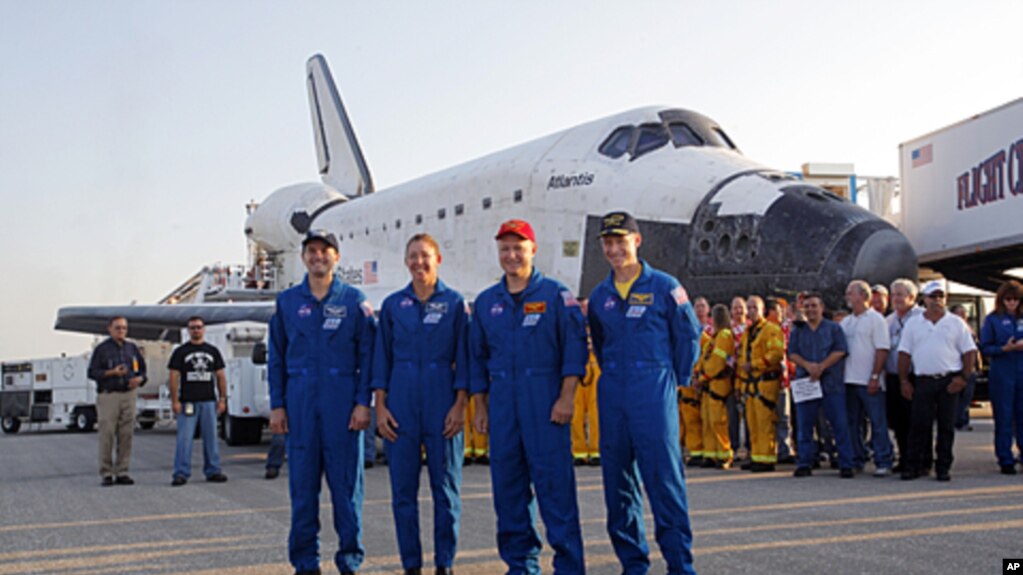The STS- 135 crew stands next space shuttle Atlantis shortly after landing at the Kennedy Space Center at Cape Canaveral, Florida, July 21, 2011