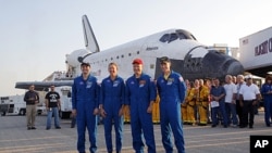 The STS- 135 crew stands next space shuttle Atlantis shortly after landing at the Kennedy Space Center at Cape Canaveral, Florida, July 21, 2011