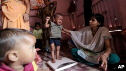 FILE - A volunteer weighs a malnourished child at the Apanalay center in Mumbai, India. A new study indicates that in the same way that lack of food can harm children, violence, deprivation and neglect are also damaging their brain circuitry.