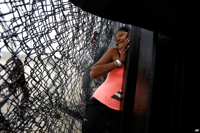 A Honduran migrant, followed by her daughter, squeezes through a gap in the U.S. border wall from Tijuana, Mexico, onto U.S. soil near Imperial Beach, California, Dec. 9, 2018.