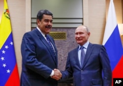 Russian President Vladimir Putin, right, shakes hands with his Venezuelan counterpart Nicolas Maduro during their meeting at the Novo-Ogaryovo residence outside in Moscow, Russia, Dec. 5, 2018.