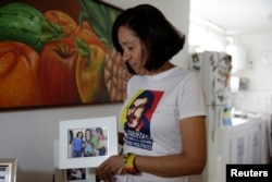 FILE - Elky Arellano, wearing a T-shirt depicting her husband, Marcelo Crovato, holds a photo of them with their children during an interview with Reuters in Caracas, Venezuela, Nov. 17, 2016.