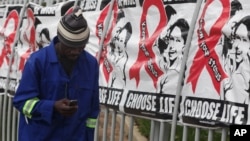 A man makes a call on a mobile phone as he passes past a World AIDS Day banners on the perimeter of an office building in Sandton, Johannesburg, South Africa, Dec. 1, 2014. 