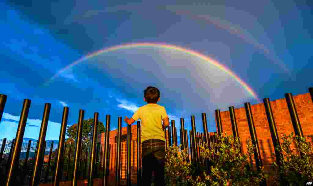 نگاه یک پسر بچه به رنگین کمان به هنگام غروب آفتاب در بوگوتا کلمبیا