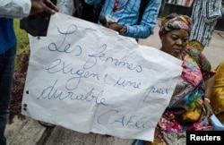 A Congolese woman holds a placard reading "Women require stable peace" as she and others protest outside talks between the opposition and the government of President Joseph Kabila at the Conference episcopale nationale du Congo (CENCO) headquarters in Kinshasa, D.R.C., Dec. 31, 2016.