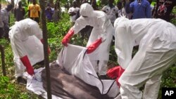 Hearth workers cover the body of a man suspected of dying from the Ebola virus on the outskirts of Monrovia, Liberia on Oct. 31, 2014. 