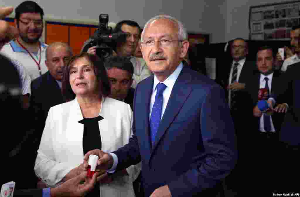 Oposisi utama Turki dan pemimpin Partai Rakyat Republik, Kemal Kilicdaroglu, dan istrinya Selvi Kilicdaroglu berbicara dengan para pejabat setelah memberikan suara di TPS di Ankara (7/6).(AP/Burhan Ozbilici)