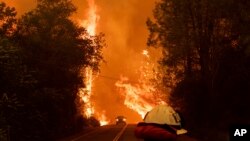 A car passes through flames on Highway 299 as the Carr Fire burns through Shasta, Calif., July 26, 2018. Fueled by high temperatures, wind and low humidity, the blaze destroyed more than 500 structures and has killed two firefighters.