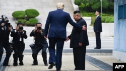 Le président des États-Unis, Donald Trump, pénètre dans la partie nord de la ligne de démarcation militaire qui sépare la Corée du Nord et la Corée du Sud, sous le regard du dirigeant nord-coréen Kim Jong Un, le 30 juin 2019. (Photo Brendan Smialowski / AFP)