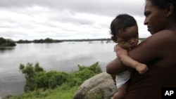 An indigenous woman holds her child near the Xingu River at the Araras tribe, near Altamira, northern Brazil, April 28, 2010. After nearly three decades of sometimes violent protests, about 1,000 other indigenous people in the remote region have resigned 