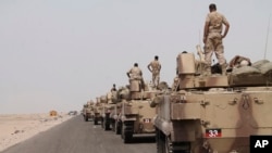 In this photo taken on Monday, Aug. 3, 2015, fighters against Shiite rebels known as Houthis stand on their armored vehicles on a road leading to Al-Anad base near Aden in the southern province of Lahej, Yemen.