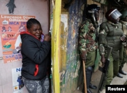 A woman cries as she takes cover during clashes between supporters of opposition leader Raila Odinga and policemen in Kibera slum, Nairobi, Kenya, Aug. 12, 2017.