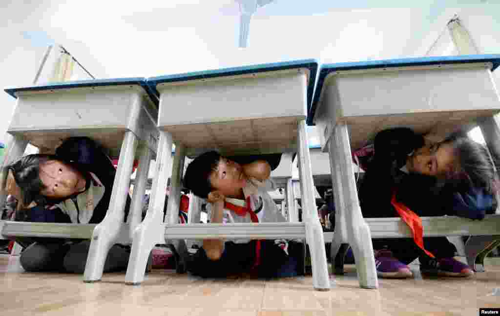 Primary school students take part in an earthquake drill ahead of the 10th anniversary of the 2008 Sichuan earthquake, inside a classroom in Handan, Hebei province, China.