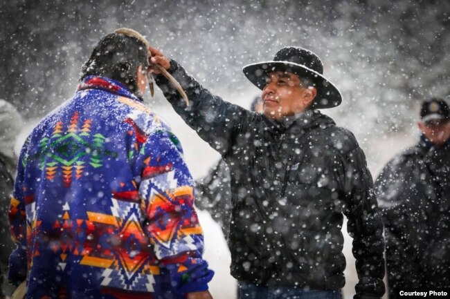 Photo shows cultural advisor Craig Falcon (R) blessing Roger Vielle, both members of Blackfeet tribe, during a Vietnam veterans retreat on the Blackfeet Reservation in Montana, September 2017. Courtesy, Wingspan Media Productions.