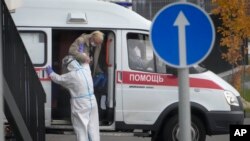 A medical worker helps a patient suspected of having coronavirus to leave an ambulance at a hospital in Kommunarka, outside Moscow, Russia, Oct. 12, 2021. 