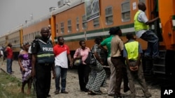 FILE - A policeman stands guard as people try to board a train on the Lagos to Kano route in Lagos, Nigeria. 