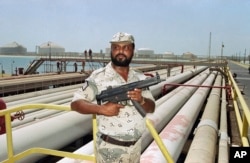 FILE - A security guard keeps watch over oil pipelines in Aramco refinery in Saudi Arabia in September 1990.