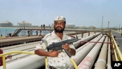 FILE - A security guard keeps watch over oil pipelines in Aramco refinery in Saudi Arabia.