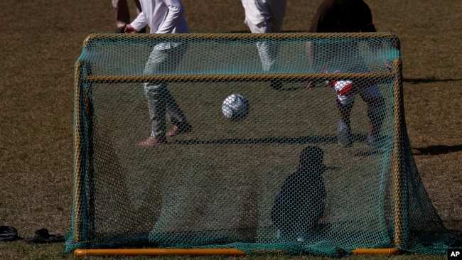 Pengungsi Afghanistan bermain sepakbola di taman bermain Institut Pengembangan Sumber Daya Manusia Nasional di Jincheon, Korea Selatan, 13 Oktober 2021. Para pengungsi muncul di hadapan publik untuk pertama kalinya sejak mereka tiba pada akhir Agustus. (Jeon Heon-kyun via AP)