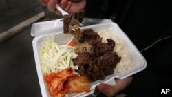 A customer in New York holds a container of Bulgogi, a Korean dish of thin beef slices marinated and grilled on a barbecue.
