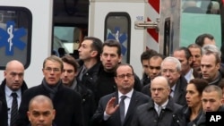Presiden Perancis Francois Hollande (tengah), dikelilingi petugas keamanan saat tiba di luar lokasi penembakan di Paris (7/1). (AP/Remy De La Mauviniere) 