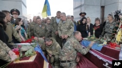 FILE - Ukrainian soldiers pay their respects during a memorial service for comrades killed in the conflict with pro-Russia separatists in Ukraine's eastern Donetsk region, in Independence Square in Kyiv, Ukraine, May. 26, 2016.