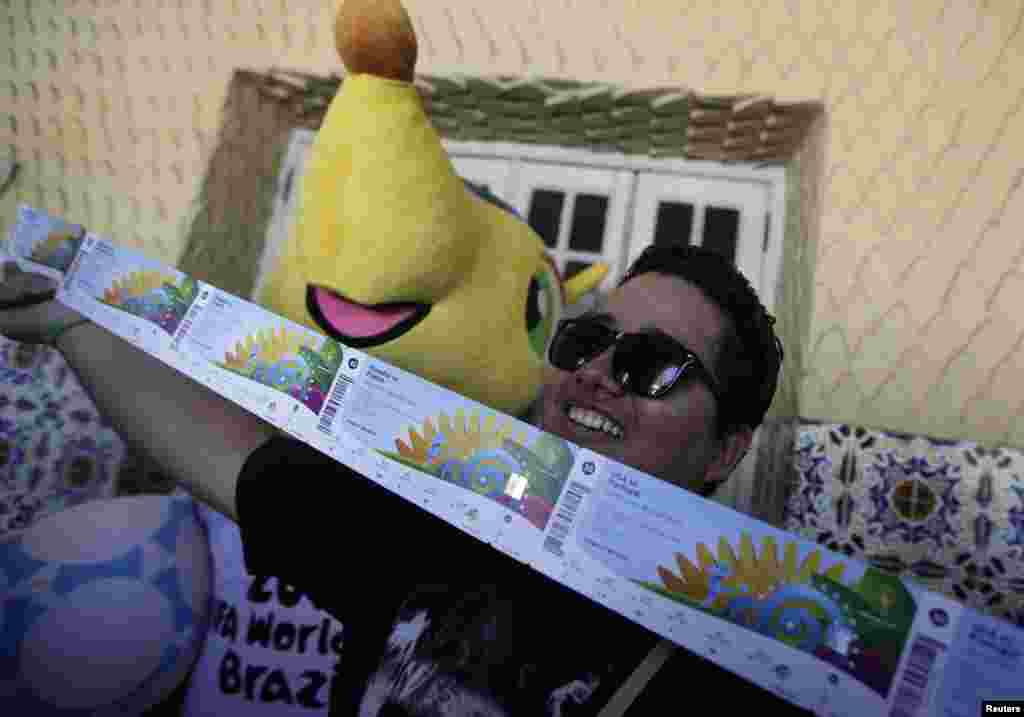 Um fã de futebol posa para a foto após comprar os seus bilhetes para o Mundial. Ao seu lado a mascote &quot;Fuleco&quot;. Rio de Janeiro Abril 18, 2014. REUTERS/Rica