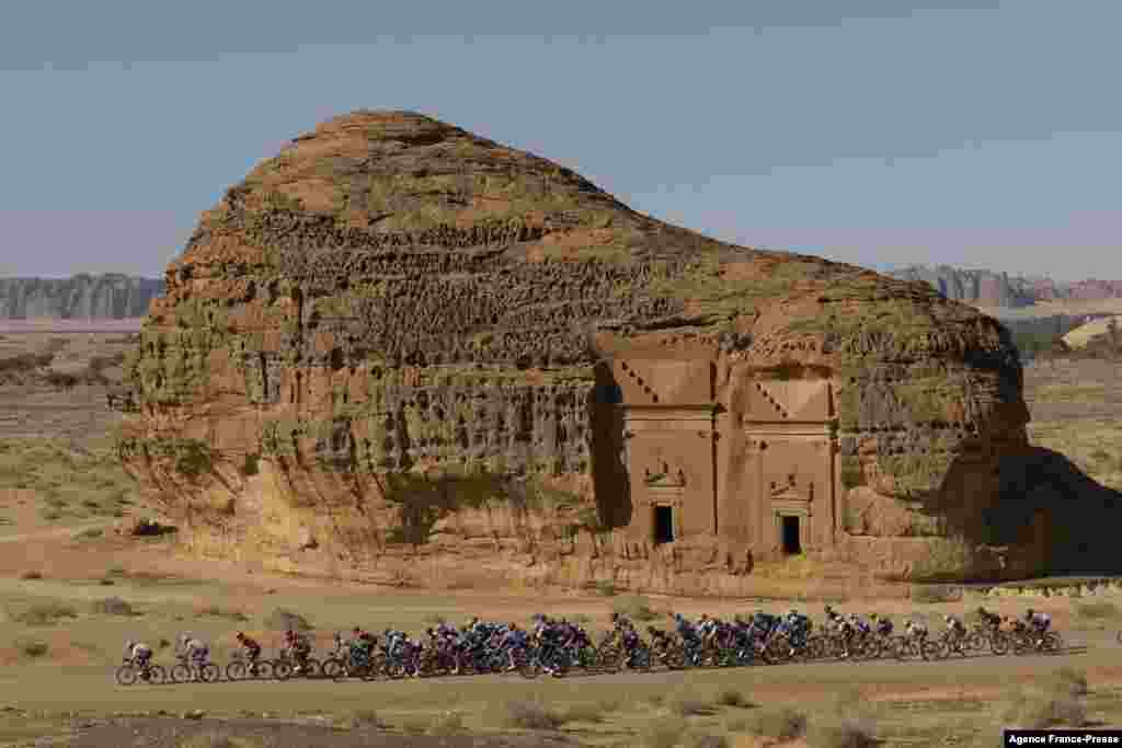 The peloton passes by ancient Nabataean carved tombs as it crosses the archaeological site of al-Hijr (Hegra), during the first stage of the Saudi Tour from Winter Park near Saudi Arabia&#39;s northwestern city of al-Ula.