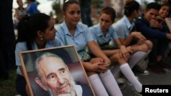 Des étudiants tiennent une image du feu président Fidel Castro attendant le passage de la caravane accompagnant la cendre de celui-ci à Camaguey, Cuba, 1er décembre 2016. 