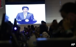 A projection screen shows Japanese Prime Minister Shinzo Abe deliver his speech during a plenary session at the Asia-Africa Summit in Jakarta, Indonesia, April 22, 2015.