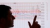 FILE - A seismologist poses for the media as he points to a seismographic graph.