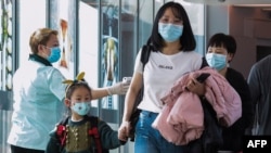 Petugas kesehatan (kiri) memeriksa penumpang yang datang dari China di bandara Internasional Changi di Singapura pada 22 Januari 2020 saat pihak berwenang meningkatkan tindakan melawan virus corona. (Foto: AFP/Roslan)