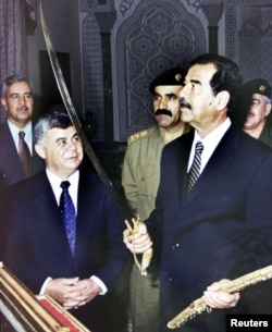 Former Iraqi president Saddam Hussein examines a sword as he received the Syrian prime minister Mustapha Miro in 2001.