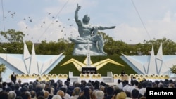 Doves fly over the Peace Statue in Nagasaki's Peace Park during a ceremony commemorating the 70th anniversary of the bombing of the city, in Nagasaki, Japan, in this photo taken by Kyodo, Aug. 9, 2015. 