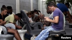 Los jóvenes cubanos se conectan a internet gracias a la conexión gratuita afuera del estudio del artista cubano Alexis Leyva "Kcho". 