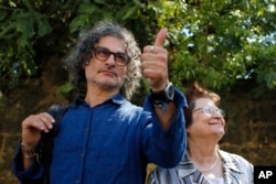 Lebanese film director Ziad Doueiri, left, gives a thumbs up next to his mother, Wafiqa, as he speaks to journalists after being released by a military court, in Beirut, Lebanon, Sept. 11, 2017.