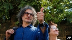 Lebanese film director Ziad Doueiri, left, gives a thumbs up next to his mother, Wafiqa, as he speaks to journalists after being released by a military court, in Beirut, Lebanon, Sept. 11, 2017. 