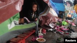 25일 미국과 멕시코 국경지역 멕시코 티후아나에서 어린 아이가 임시로 마련된 거처에 앉아 비를 피하고 있다. (자료사진) 