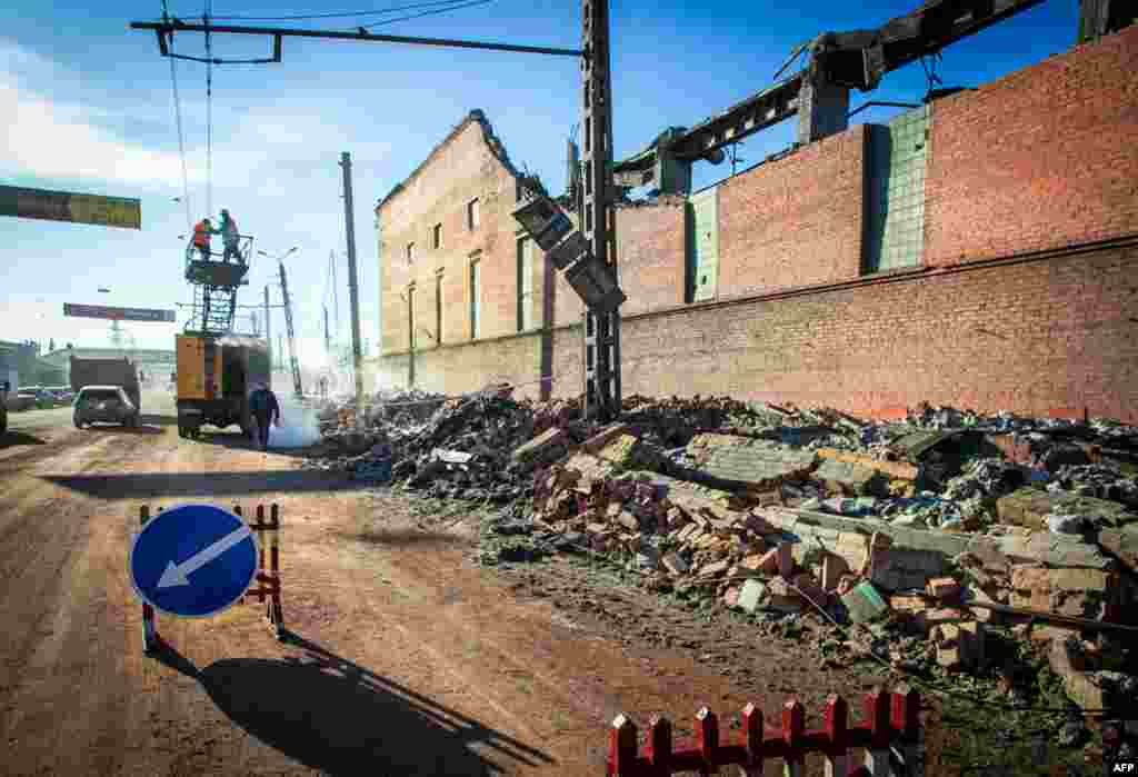 Công nhân sửa chữa một đường dây điện gần các bức tường của một nhà máy kẽm ở địa phương bị phá hủy do chấn động do thiên thạch đâm xuống thành phố Chelyabinsk ở Nga, ngày 15 tháng 2, 2013.