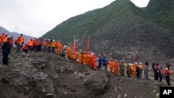 Rescue workers line up along a giant pit as they prepare to search for victims at the site of a landslide in Maoxian County in southwestern China's Sichuan Province, June 25, 2017.