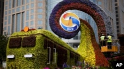 Workers on a platform install flowers on a display in a shape of a train to promoting the upcoming Belt and Road Forum in Beijing, China, April 23, 2019.