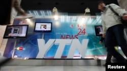A TV crew walks by at the main office of television network YTN, in Seoul, March 20, 2013.