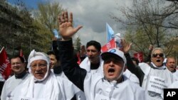 FILE - Thousands of civil servants and members of Turkish unions wear placards that read "no to corruption" as they march to protest against the government's new labor regulations and economy policies in Ankara, April 4, 2015. 